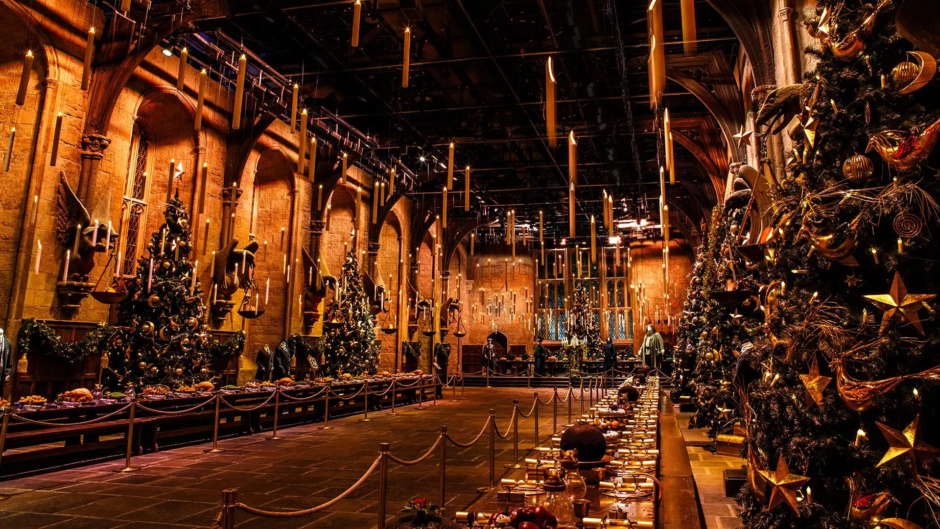Hogwarts in the Snow - the Great Hall set dressed for Christmas with Christmas trees, a feast and floating candles