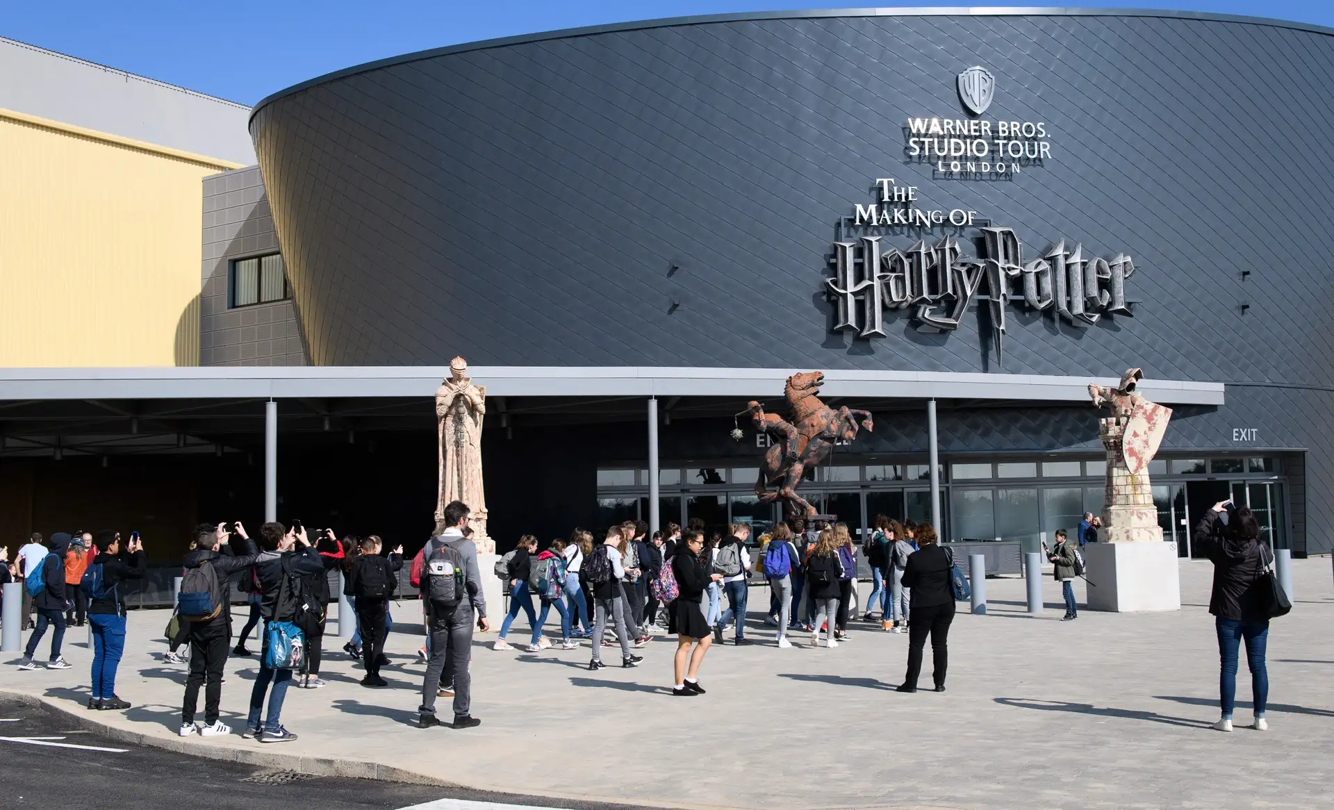Visitors outside Warner Bros. Studio Tour London entrance with film statues